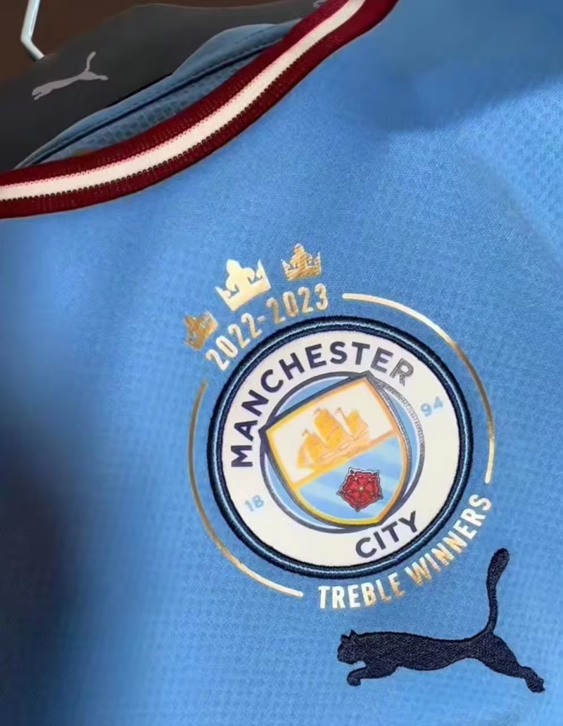 Camisa Oficial do Manchester City 22/23 - Tríplice Coroa